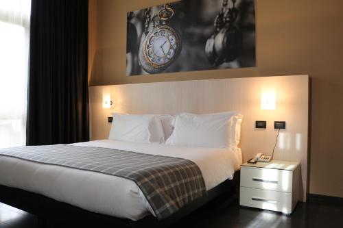 韦尔切利加里波第酒店的一张位于酒店客房的床铺,墙上挂着一个时钟