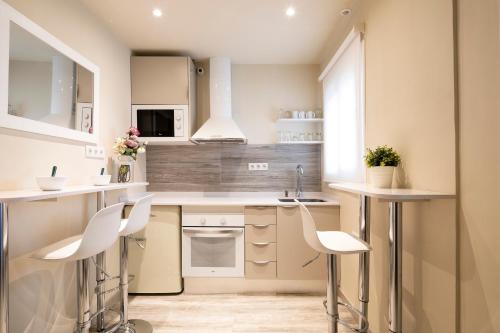 巴塞罗那Chic Gran Via Apartment的厨房配有白色的柜台和白色的椅子