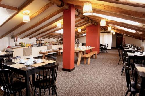 库斯科Abittare Hotel的一间设有桌椅的餐厅,位于带木制天花板的房间内
