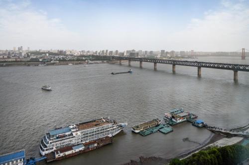 武汉武汉晴川假日酒店 的一条有两艘游轮和一座桥梁的河流