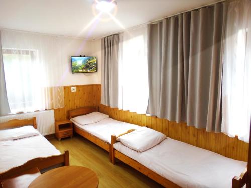 普热谢卡Ośrodek Wczasowy Zielona Gospoda的一间设有三张床的客房,墙上设有一台电视。
