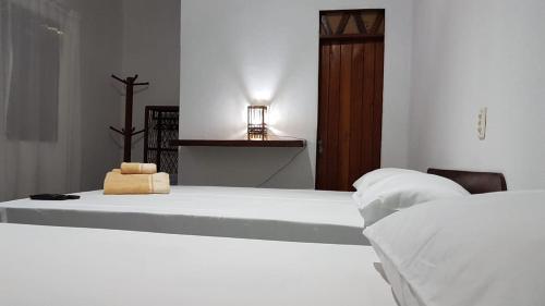 巴拉格兰德Casa Antiga Hospedagem的白色卧室配有两张床和一张桌子上的灯
