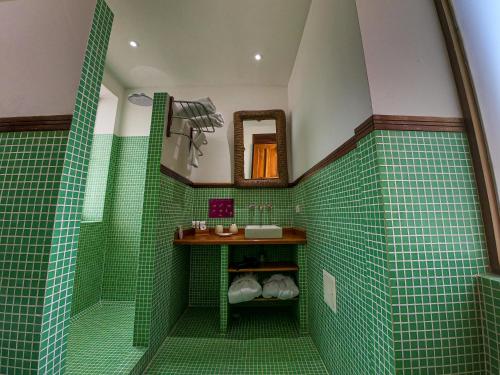 圣玛尔塔卡萨伊莎贝拉，卡利酒店的绿色瓷砖浴室设有水槽和镜子