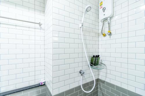 曼谷Be Wish Residence的白色瓷砖浴室内带软管的淋浴