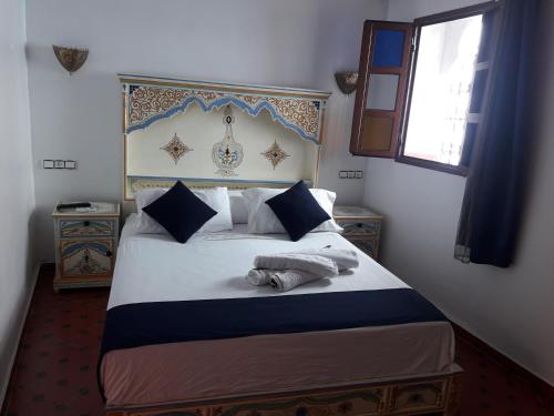 舍夫沙万Casa El Haouta的一间卧室配有一张带蓝色和白色床头板的床