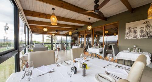 奥茨胡恩德兹科农家乐酒店的餐厅设有白色的桌椅和窗户。