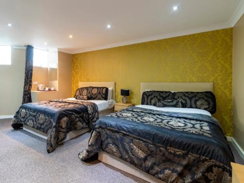 卢顿Stuart Hotel的一间卧室设有两张床和黄色的墙壁