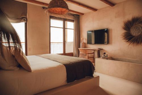 哈维亚Nomad Hotel - Xábia Port的一间卧室设有一张床、一台电视和一个窗口。
