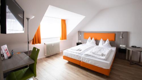 卡尔斯鲁厄阿斯托里亚酒店的一间卧室配有橙色和白色的床以及书桌。