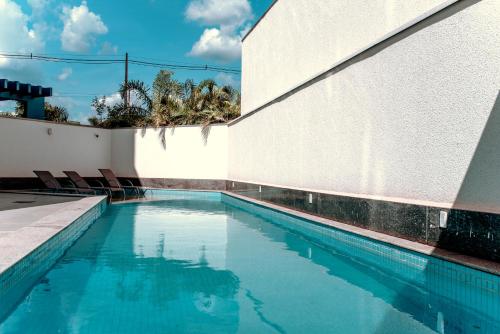帕尔马斯Hplus Premium Palmas的白色墙壁旁带椅子的游泳池