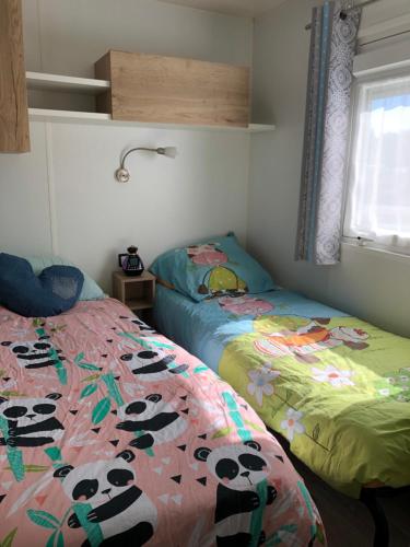 波讷地区圣朱利安Mobile Home - Les Dunes de Contis的一间卧室配有两张床,床上铺有熊猫