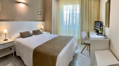 圣卡洛斯拉腊皮塔Hotel Restaurant Llansola的酒店客房设有一张大床和一张书桌。