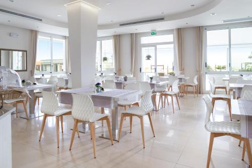 贝拉里亚-伊贾马里纳里维埃拉酒店的餐厅设有白色的桌椅和窗户。