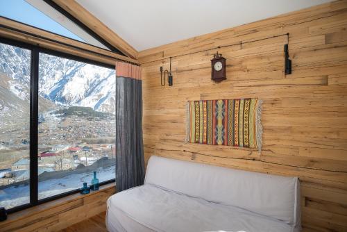 卡兹贝吉Kazbegi cabins的一间卧室设有一张床、一个窗口和一个时钟