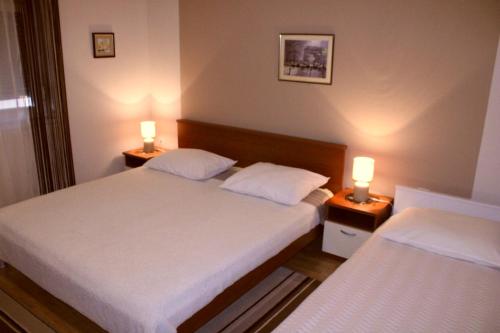 扎达尔Apartments Silvana sunset view的配有两张床铺的房间,桌子上放着两盏灯