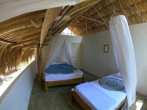 埃尔扎伊诺Hotel Jasayma dentro del Parque Tayrona的带茅草屋顶的客房内的两张床