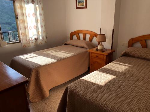贝纳马奥马Benamahoma Rural的一间卧室设有两张床、一个窗口和一张桌子