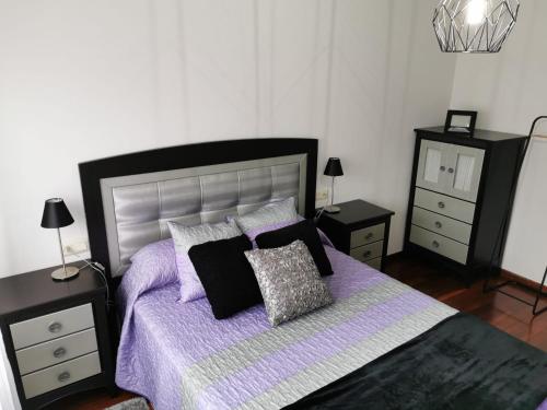 马林Casa Álvaro的一间卧室配有一张带紫色床单和枕头的床。