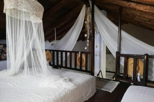 霍里顿Lost Paradise的卧室配有带白色窗帘的天蓬床