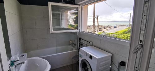 孔卡尔诺Studio face à la mer的一间带水槽和洗衣机的浴室以及窗户。