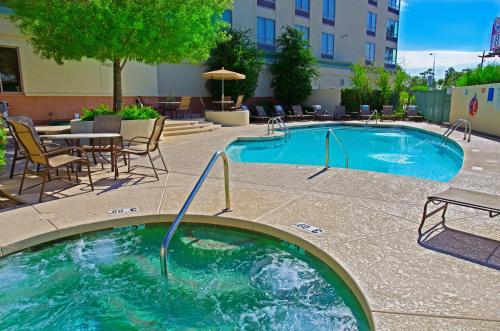 凤凰城Holiday Inn & Suites Phoenix Airport, an IHG Hotel的一座带桌椅的游泳池以及一座建筑
