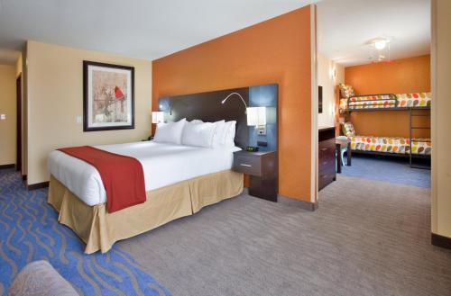 伍德森特瑞斯Holiday Inn Express & Suites St Louis Airport, an IHG Hotel的一间设有大床和楼梯的酒店客房