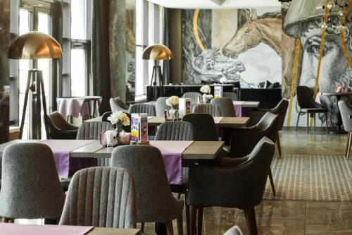 伊尔库茨克贝加尔湖商业中心酒店的一间带桌椅和马壁画的餐厅