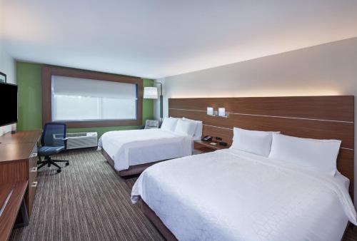 布伦纳姆Holiday Inn Express & Suites - Brenham South, an IHG Hotel的酒店客房设有两张床和电视。