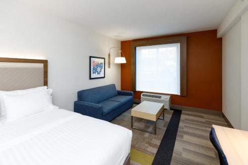 斯特布里奇Holiday Inn Express & Suites - Sturbridge, an IHG Hotel的酒店客房,配有床和蓝色的沙发