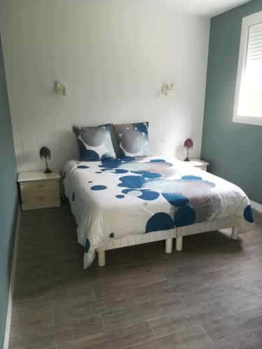 佩萨克La KLEMALINE的一间卧室配有一张带蓝色和白色棉被的床