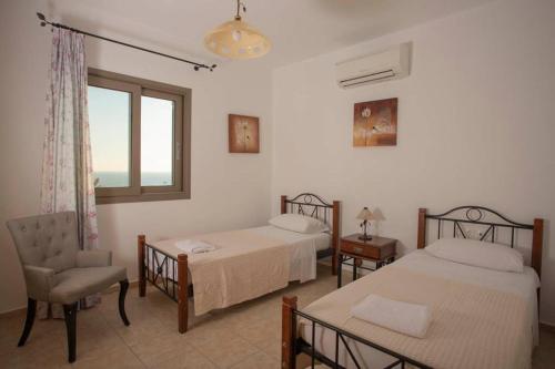斯巴达Villa Helios的一间卧室设有两张床、一把椅子和一个窗户。