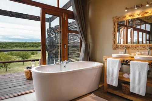 纳姆比提动物保护区Cheetah Ridge Lodge的带浴缸的浴室和大窗户