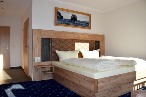 罗迪斯海恩沃尔夫斯穆尔菲林酒店的一间卧室配有一张大床和木制床头板