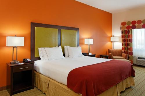 弗洛伦斯佛罗伦萨东北部智选假日酒店的一张大床,位于酒店带橙色墙壁的房间