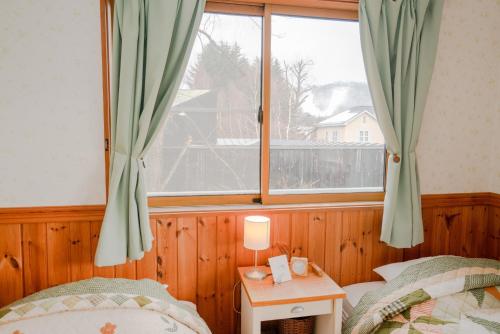 轻井泽Guest House Chaconne Karuizawa的一间卧室设有两张床和大窗户