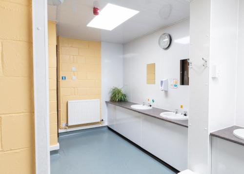 托里登托里登青年旅舍的浴室设有两个水槽,墙上有时钟