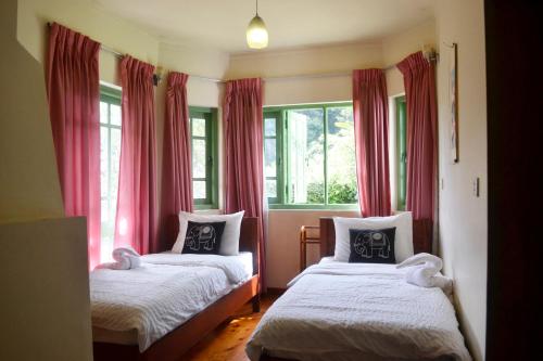 努沃勒埃利耶塞姆里假日简易别墅住宿加早餐旅馆的一间卧室设有两张床,窗户配有红色窗帘