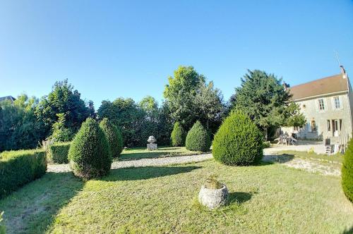 克莱尔沃雷拉克Gîte Jura Lac Emeraude的一座花园,在一座建筑前有树木和灌木
