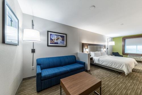 沃思堡Holiday Inn Express & Suites Fort Worth - Fossil Creek, an IHG Hotel的酒店客房,配有床和蓝色的沙发