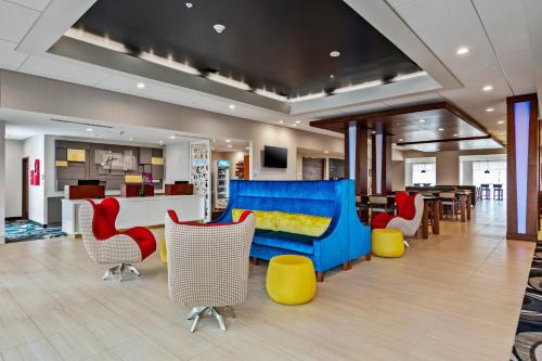 奥兰多Holiday Inn Express & Suites Orlando- Lake Buena Vista, an IHG Hotel的大堂设有蓝色的沙发和色彩缤纷的椅子