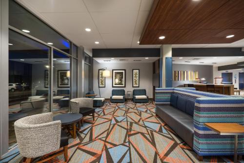 辛普森维尔Holiday Inn Express & Suites Greenville SE - Simpsonville, an IHG Hotel的一间设有椅子、一张沙发和桌子的等候室