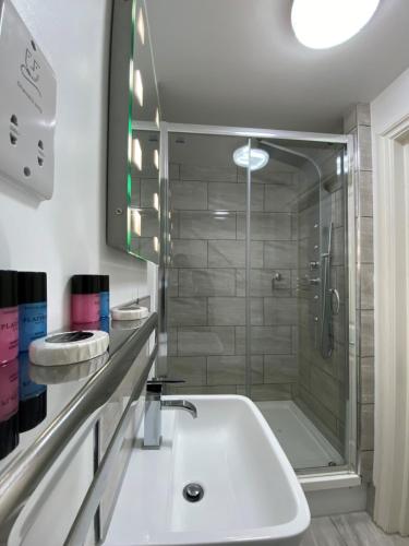 查塔姆The Charles Hotel的带淋浴和白色盥洗盆的浴室