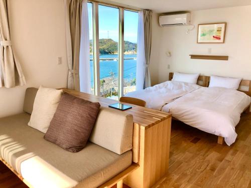 直岛町MY LODGE Naoshima的一张沙发和一个窗户的客房内的两张床