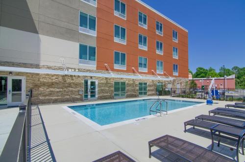 莫比尔Holiday Inn Express & Suites Mobile - University Area, an IHG Hotel的大楼前的游泳池