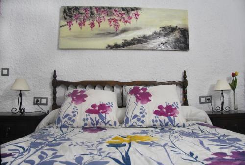 GraenaCuevas Cañada de las Piedras的一张带两个枕头的床和墙上的绘画