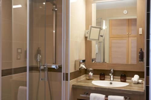 波尔多Hotel Vatel Bordeaux的浴室配有盥洗盆和带镜子的淋浴
