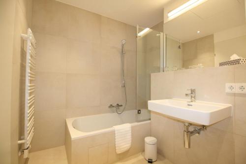 维也纳Your Living Vienna CBD的白色的浴室设有水槽和浴缸。