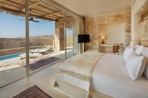 Shaharut撒哈鲁特六善酒店的卧室设有一张白色大床和大窗户
