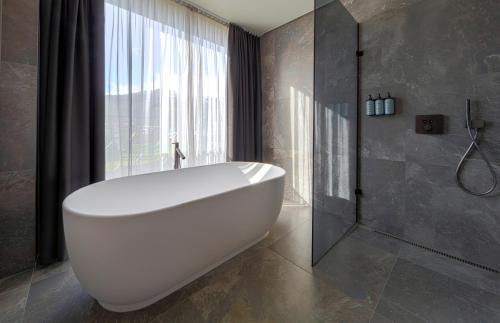 盖锡尔Hotel Geysir的带窗户的浴室内的白色浴缸