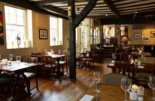 伍斯特Ye Olde Talbot Hotel by Greene King Inns的餐厅设有木桌、椅子和窗户。